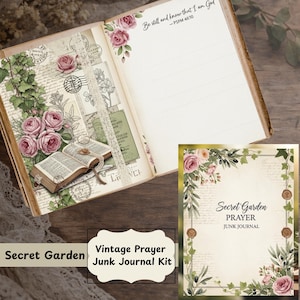 May include: An open vintage-style journal with floral and botanical illustrations, including roses and greenery. The journal features a lace ribbon bookmark and the text "Be still and know that I am God." A "Secret Garden" prayer junk journal kit is also visible.