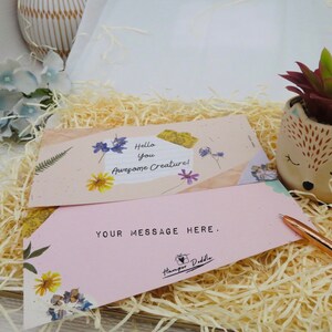 May include: A gift box with decorative paper, two cards with floral accents, and a small succulent in a fox-shaped pot. One card reads "Hello You Awesome Creature!" and the other says "YOUR MESSAGE HERE."