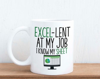 Può includere: Tazza da caffè in ceramica bianca con un design nero e verde. La tazza recita "Excel-lent at my job I know my sheet" con un'icona di monitor di computer verde con un foglio di calcolo e un grafico a torta.