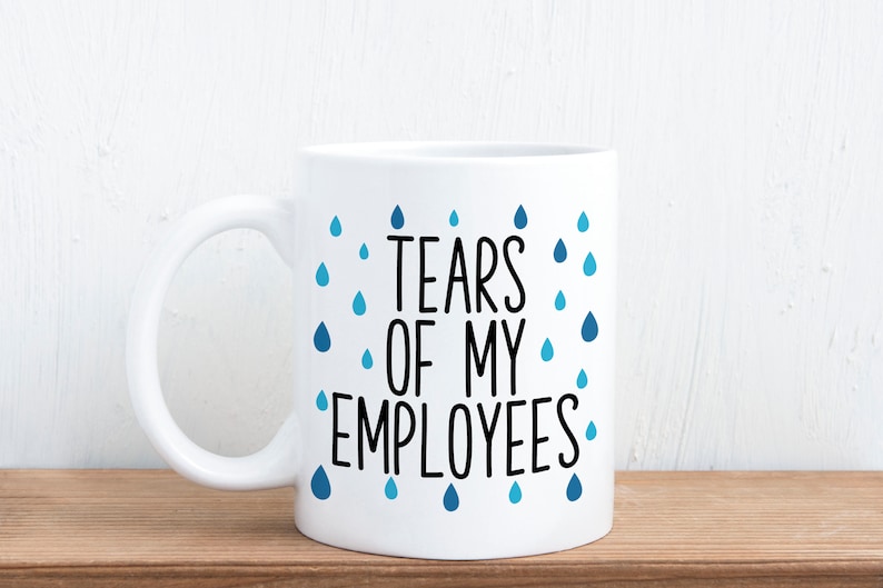 May include: White ceramic coffee mug with a black and blue design. The mug has a black text that reads "Tears of my employees" with blue raindrops surrounding the text.