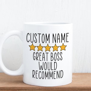 May include: A white ceramic mug featuring black text that reads CUSTOM NAME, GREAT BOSS, WOULD RECOMMEND, positioned above and below a row of five yellow stars with black outlines, centred on the front of the mug with a curved handle on the left.