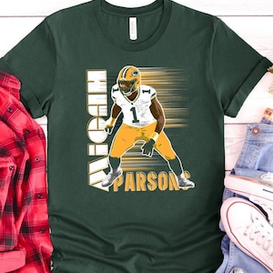 May include: Green t-shirt featuring a football player in a yellow and white uniform. The shirt has the name "HIGH PARSON" in white block letters. The player is in a dynamic pose with a blurred background.