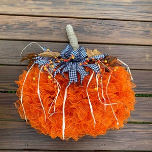 K&ouml;nnte beinhalten: Orangefarbener und wei&szlig;er Mesh-K&uuml;rbis-Adventskranz mit einer schwarz-wei&szlig;en Karoband und Herbstbeeren.