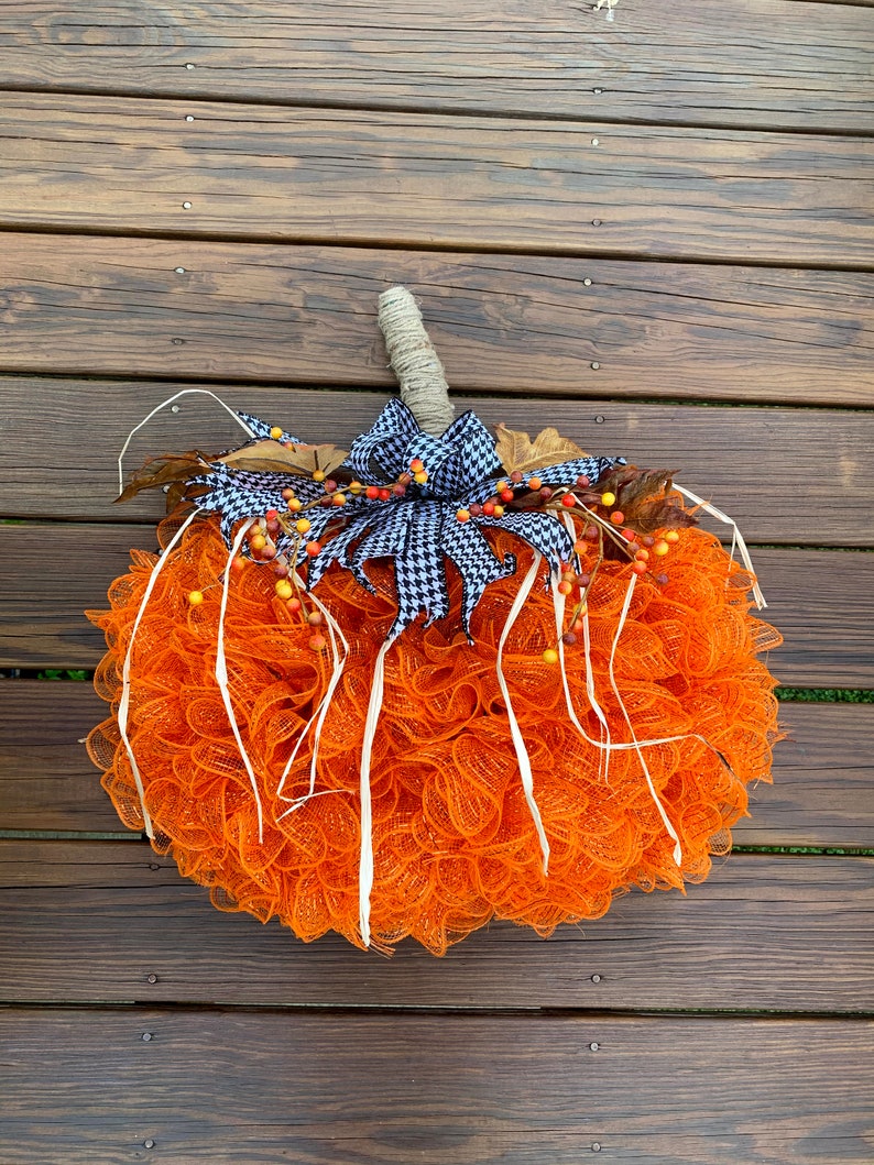 K&ouml;nnte beinhalten: Orangefarbener und wei&szlig;er Mesh-K&uuml;rbis-Adventskranz mit einer schwarz-wei&szlig;en Karoband und Herbstbeeren.