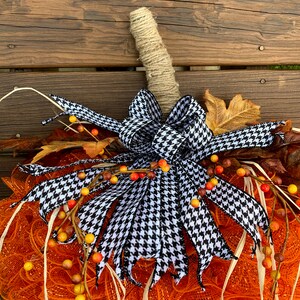 K&ouml;nnte beinhalten: Orangefarbener und wei&szlig;er Mesh-K&uuml;rbis-Adventskranz mit einer schwarzen und wei&szlig;en Hahnentritt-Schleife und Herbstlaub-Akzenten.