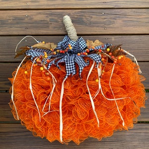 K&ouml;nnte beinhalten: Orangefarbener und wei&szlig;er Mesh-K&uuml;rbis-Adventskranz mit einer schwarz-wei&szlig;en Karoband und Herbstbeeren.