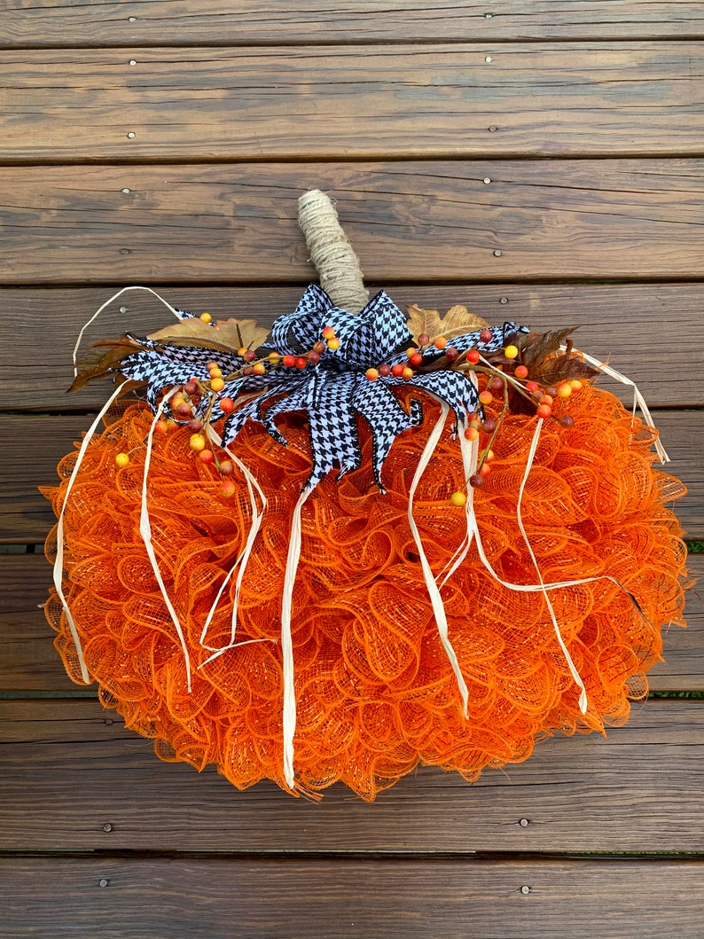 K&ouml;nnte beinhalten: Orangefarbener und wei&szlig;er Mesh-K&uuml;rbis-Adventskranz mit einer schwarz-wei&szlig;en Karoband und Herbstbeeren.