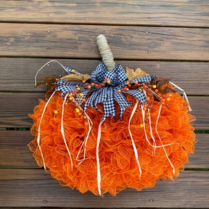 K&ouml;nnte beinhalten: Orangefarbener und wei&szlig;er Mesh-K&uuml;rbis-Adventskranz mit einer schwarz-wei&szlig;en Karobinde und Herbstbeeren.