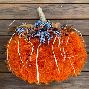 K&ouml;nnte beinhalten: Orangefarbener und wei&szlig;er Mesh-K&uuml;rbis-Adventskranz mit einer schwarz-wei&szlig;en Karoband und Herbstbeeren.