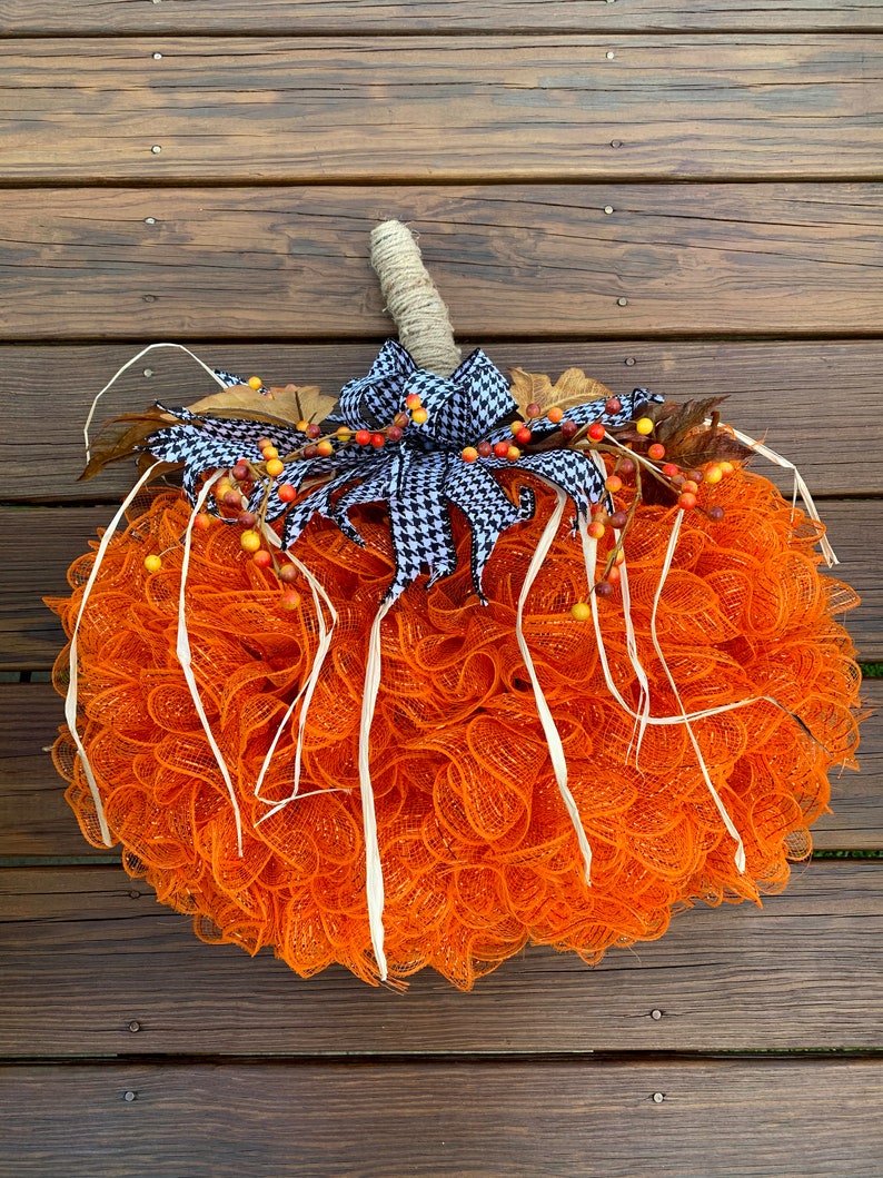 K&ouml;nnte beinhalten: Orangefarbener und wei&szlig;er Mesh-K&uuml;rbis-Adventskranz mit einer schwarz-wei&szlig;en Karoband und Herbstbeeren.