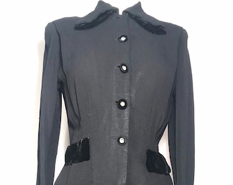 May include: A black skirt suit with a velvet trim on the collar, cuffs, and waist. The jacket has a button-up front and the skirt is knee-length.