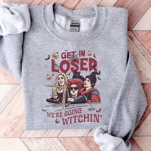May include: Gray sweatshirt with a graphic of three women dressed as witches driving in a car. The text on the sweatshirt reads "Get in Loser, We're Going Witchin'"
