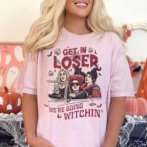 May include: Pink t-shirt with a graphic of three witches driving a car with the text "Get in Loser, We're Going Witchin'"