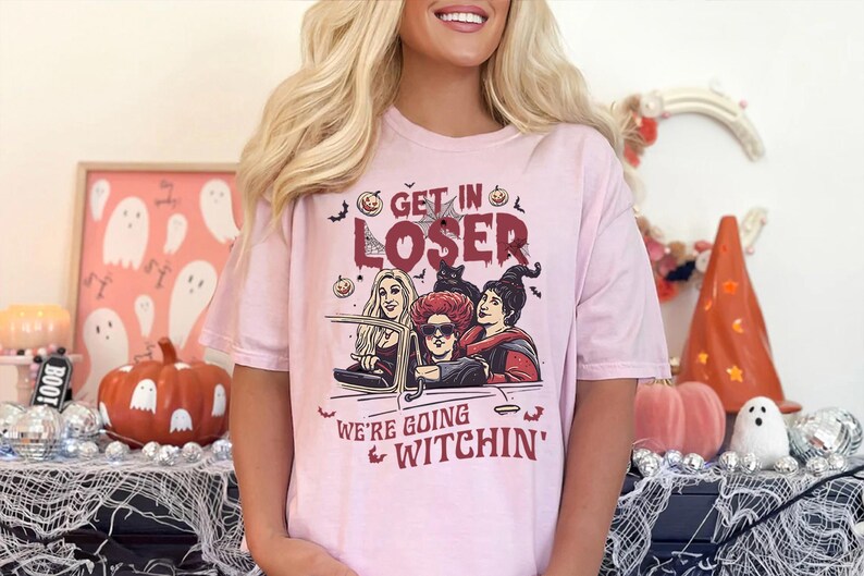 May include: Pink t-shirt with a graphic of three witches driving a car with the text "Get in Loser, We're Going Witchin'"