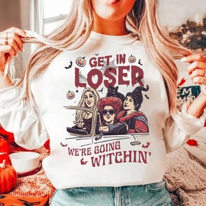 May include: White sweatshirt with a graphic of three witches driving in a car with the text "Get in Loser, We're Going Witchin'" printed on it.