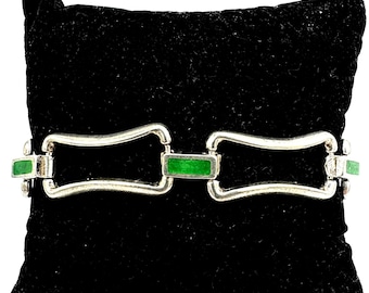 Puede incluir: Pulsera plateada con detalles rectangulares verdes. La pulsera presenta una serie de eslabones rectangulares unidos por barras plateadas curvas. Los detalles verdes están espaciados uniformemente, creando un contraste.