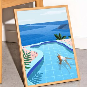 May include: A framed art print depicts a person swimming in a blue pool with a scenic ocean view. The artwork features a light blue pool with a grid pattern, surrounded by pink and green foliage. The frame is made of light brown wood.