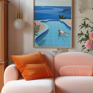 May include: A framed art print shows a person swimming in a blue pool, with a view of the sea. An orange velvet cushion rests on a pink sofa. A round, white globe light hangs from the ceiling.