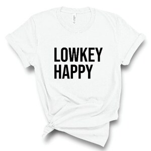Könnte beinhalten: Weißes T-Shirt mit schwarzem Text, der "LOWKEY HAPPY" lautet