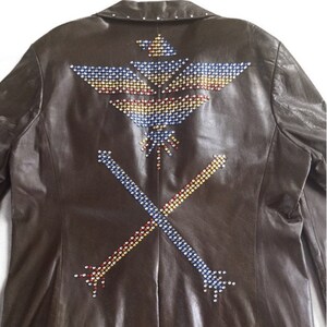 May include: A brown leather jacket with a colorful eagle and crossed arrows design made of rhinestones.