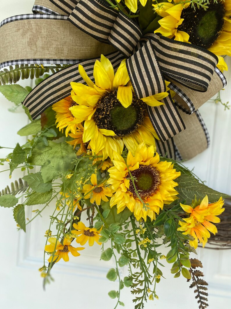 Close up of lower portion of wreath showing  sunflowers and greenery nestled into the bow.