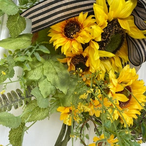 Close up of sunflowers and greenery included in the lower portion of wreath.