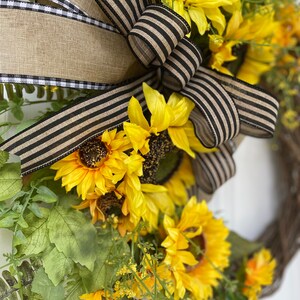 Side view of wreath showing placement of sunflowers blossoms and bow made from coordinating ribbon of burlap and black.