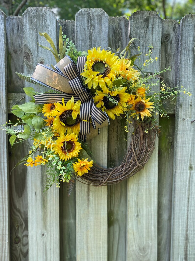 Wreath shown hanging on weathered wooden fence.