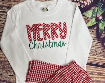 May include: White long-sleeved shirt and red gingham pajama pants. The shirt features the words "MERRY" in red gingham and "Christmas" in green script. The pajama pants are red and white gingham.