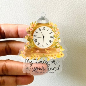 May include: A clear sticker with a vintage-style clock with floral accents. The text "My times are in your hand" and "PSALM 31:15 NKJV" is printed below the clock.