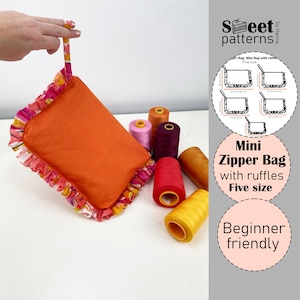 May include: An orange mini zipper bag with ruffles, held by a hand. The bag has a colorful ruffled trim. Several spools of thread in various colors are scattered around the bag. The image includes text that says "Mini Zipper Bag with ruffles Five size" and "Beginner friendly".
