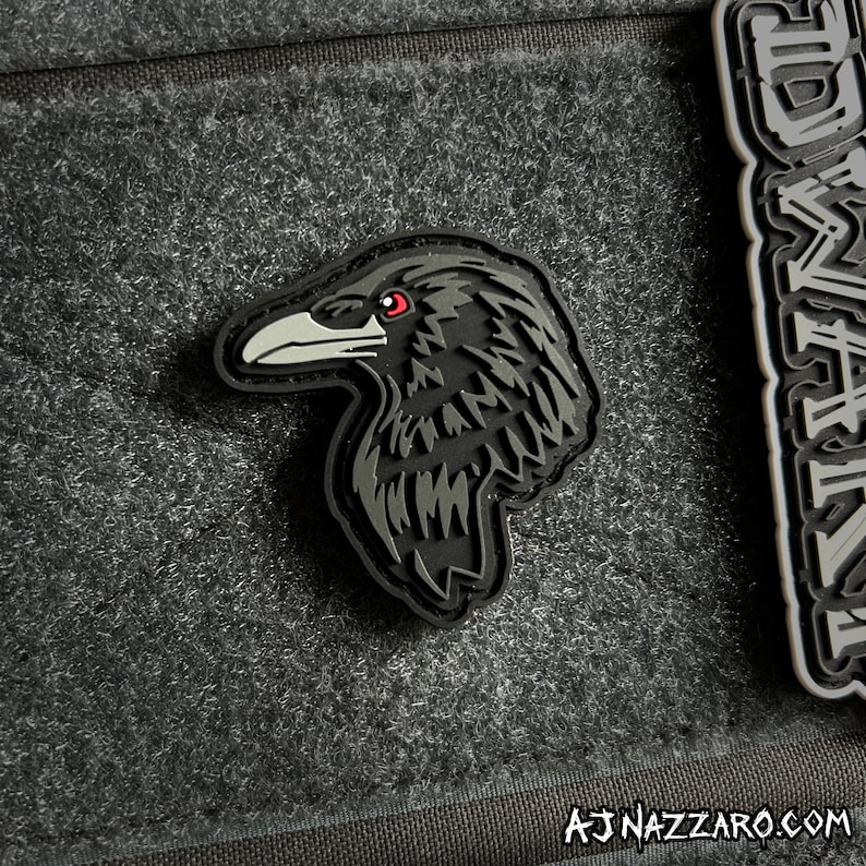 May include: Black crow patch with red eyes, a detailed design, and a textured surface. The patch is made of a durable material and is perfect for adding a touch of personality to your gear.
