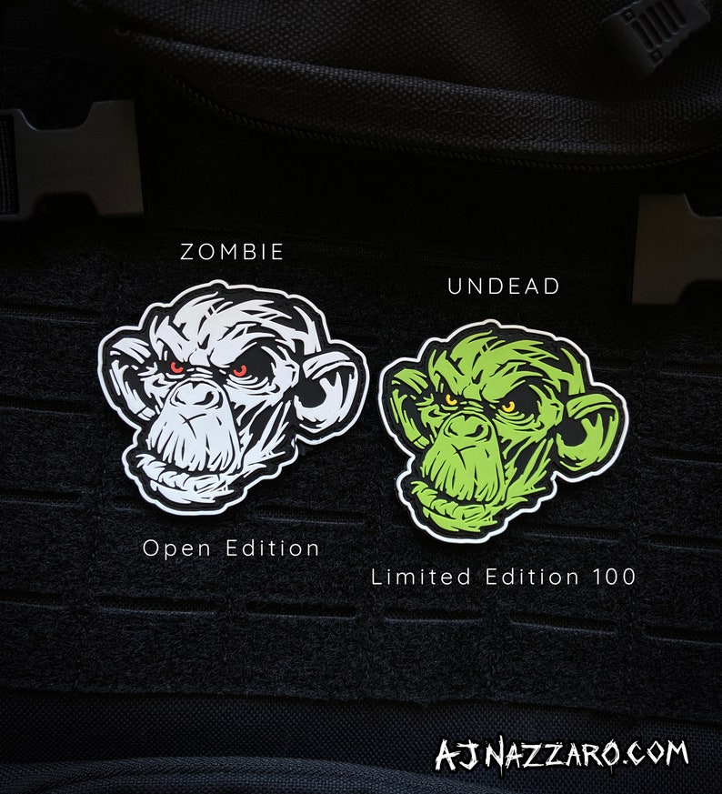 May include: Two patches featuring a stylized ape face. One is white with red eyes, labeled "ZOMBIE" and "Open Edition." The other is green with yellow eyes, labeled "UNDEAD" and "Limited Edition 100." The artist's signature is at the bottom.