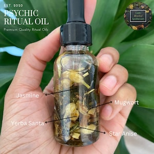 May include: A clear glass bottle filled with a blend of herbs and flowers, including mugwort, star anise, yerba santa, and jasmine. The bottle is labeled "Psychic Ritual Oil" and "Premium Quality Ritual Oils".