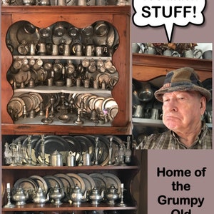 May include: A wooden cabinet filled with antique pewter dishes, plates, and mugs. The cabinet is overflowing with items, with the caption "Too Much STUFF!" above it. The caption "Home of the Grumpy Old Collector" is below the cabinet.