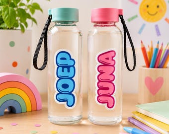May include: Two clear glass water bottles with black carrying straps. The left bottle has a light blue cap and the name JOEP in blue letters. The right bottle has a pink cap and the name JUNA in pink letters. Both bottles have a smooth finish.