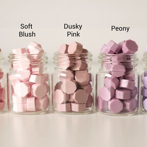 May include: Five small glass jars filled with colorful wax beads. The colors are Smoked Salmon, Soft Blush, Dusky Pink, Peony, and Soft Taro. Each jar has a label with the color name.