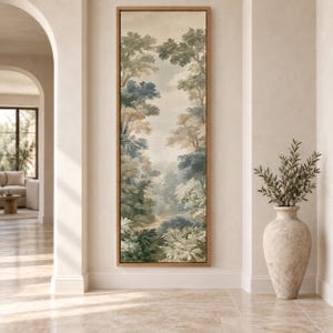 May include: A tall, vertical rectangular wall art piece framed in light wood, featuring a muted landscape painting of a dense forest with layered trees in shades of sage green, muted blue, and cream, depicting a path winding through the woods.