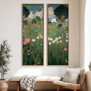 May include: Two framed landscape paintings. Each features a vibrant green field with white and pink flowers, trees, and a blue sky with clouds. The artwork is in a vertical format, with a wooden frame.