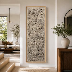 May include: A tall, rectangular wall art piece featuring a dense, intricate pattern of black vertical lines, dots, and small geometric shapes on a textured beige background, enclosed within a light-colored wooden frame hanging on a wall.