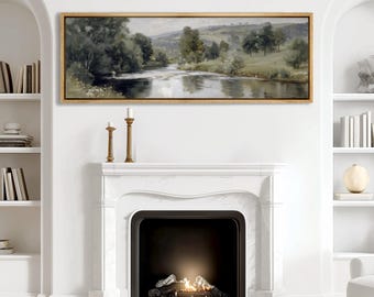 May include: A landscape painting in a gold frame depicts a serene river scene with trees and rolling hills. The artwork hangs above a white marble fireplace with a lit fire, flanked by bookshelves and decorative candles.