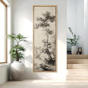 May include: A framed, vertical artwork featuring a monochrome ink wash painting of a tree on a rocky cliff. The artwork has a light beige background and a natural wood frame. The tree's branches and leaves are detailed, with a misty mountain landscape in the background.