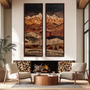 May include: Two framed wooden wall art pieces depicting a desert landscape with mountains, cacti, and layered terrain in shades of brown, tan, and black. The artwork is displayed above a fireplace with a burning fire and two armchairs.