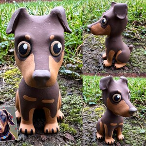 May include: A hand-painted ceramic figurine of a brown and tan dog with large eyes. The figurine is sitting on a bed of green moss.