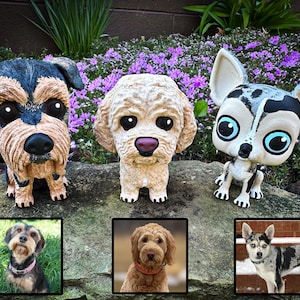 May include: Three custom-made dog figurines, each painted to resemble a different breed. The figurines are standing on a rock with a bed of purple flowers behind them.  The figurines are displayed next to photos of the real dogs they are based on.