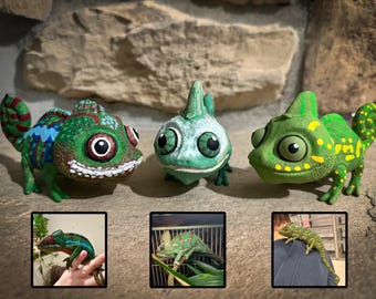 May include: Three colorful chameleon figurines in green, blue, and yellow hues. Each figurine has large, expressive eyes and detailed patterns. The image includes three smaller inset photos of real chameleons.