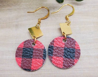 May include: A pair of gold dangle earrings with red and black buffalo plaid round charms and gold square charms.