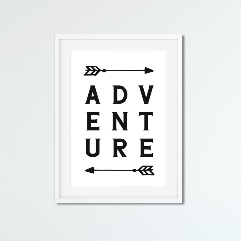 May include: A framed print with the word "ADVENTURE" in bold black letters. Two black arrows, one above and one below the word, point to the right. The print is in a white frame.