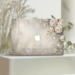 Puede incluir: Funda para portátil con diseño floral de rosas crema y follaje sobre un fondo suave, similar a una acuarela. El texto dice: "THE LORD IS MY STRENGTH AND MY SONG. Éxodo 15:2".