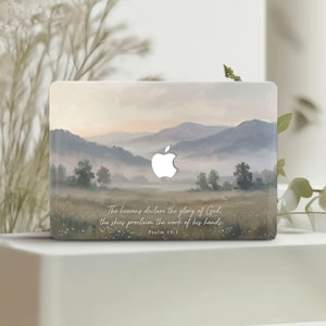 Puede incluir: Funda para portátil con una pintura de paisaje de montañas y un valle en colores suaves. El logotipo de Apple es visible. El texto en la parte inferior dice: "Los cielos proclaman la gloria de Dios; el firmamento anuncia la obra de sus manos. Salmo 19:1."
